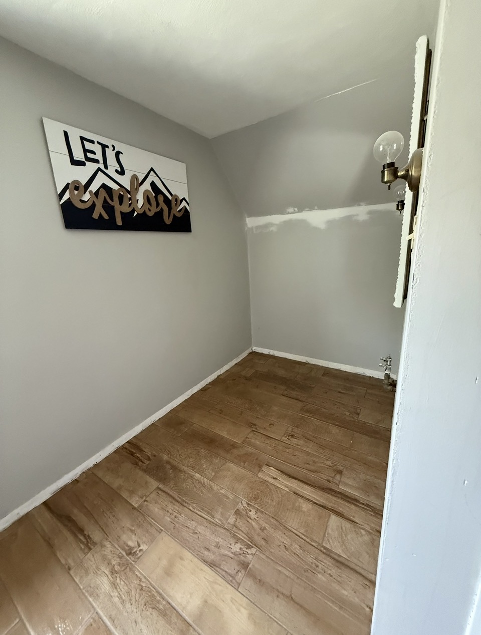 Small room after — wood-look tile floor, fresh paint, and decorative wall art