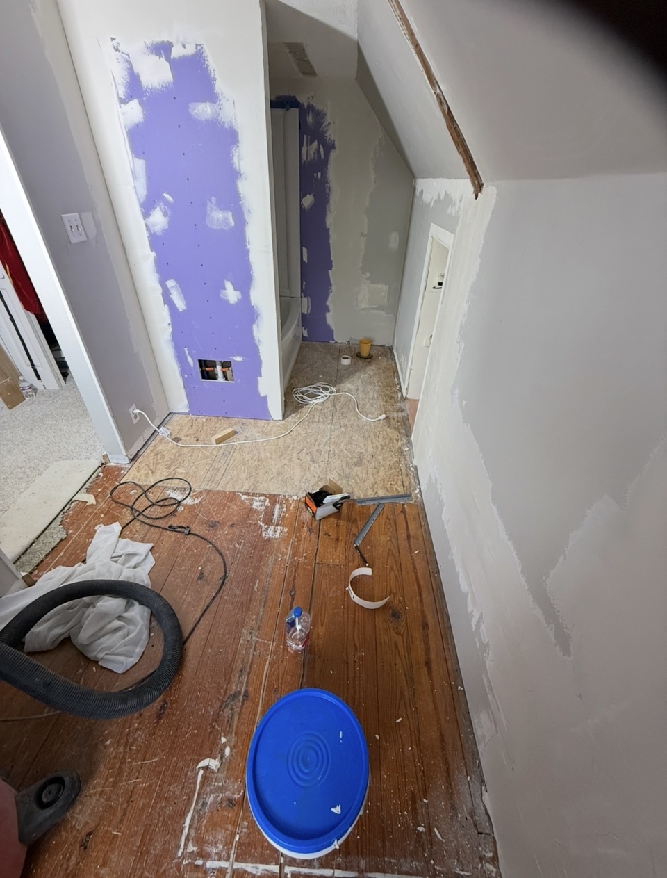 Small room before — torn-up subfloor, exposed drywall patches, and demo debris