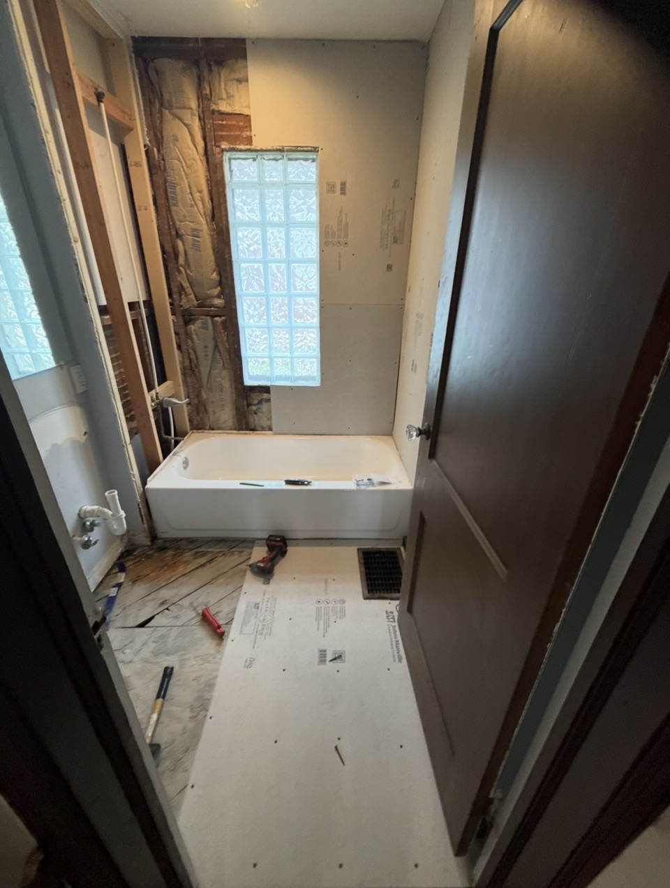 Bathroom during demo — fresh tub set, new subfloor, and walls prepped for tile