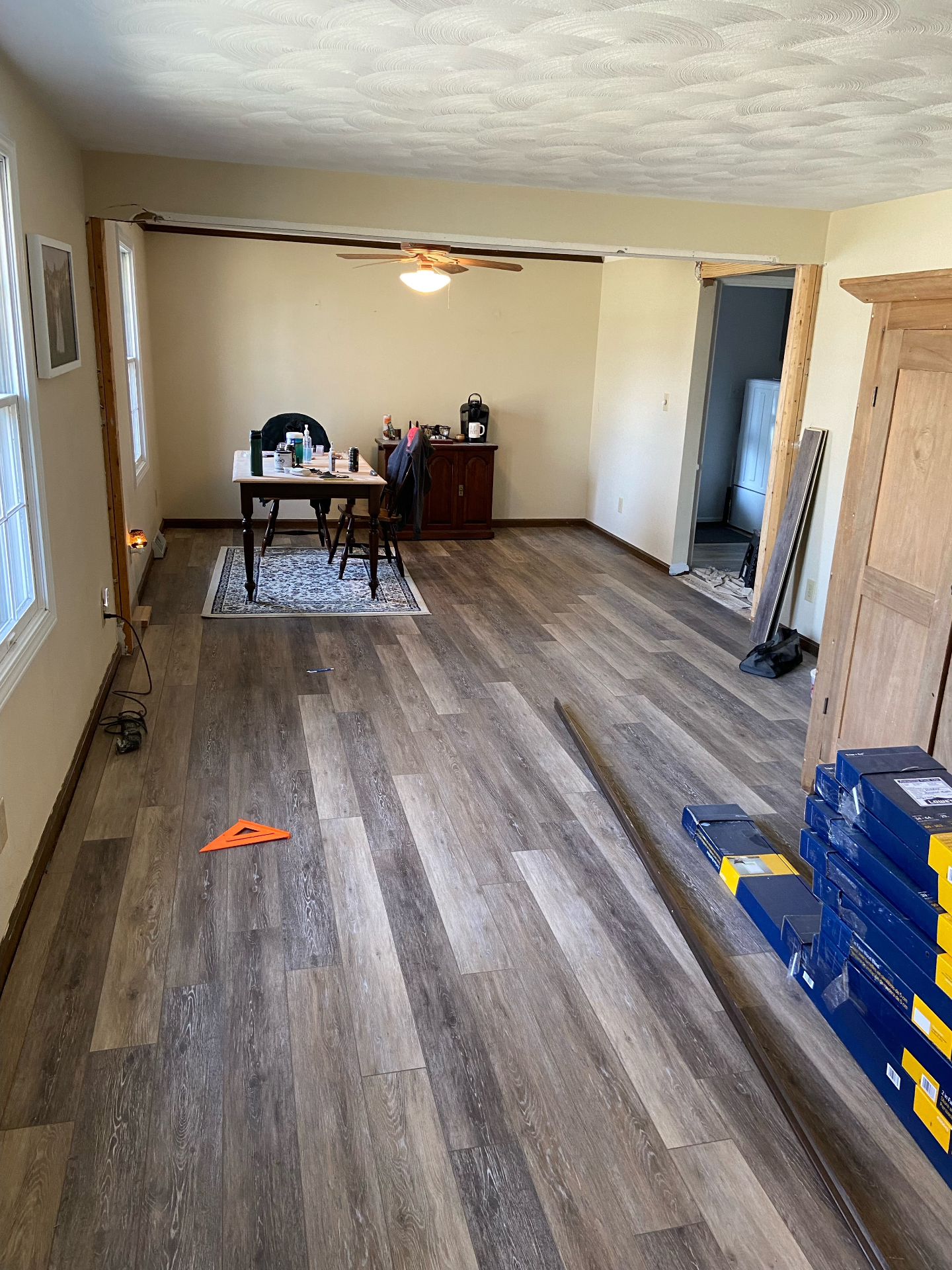 Living room after — fresh light gray luxury vinyl plank flooring mid-install