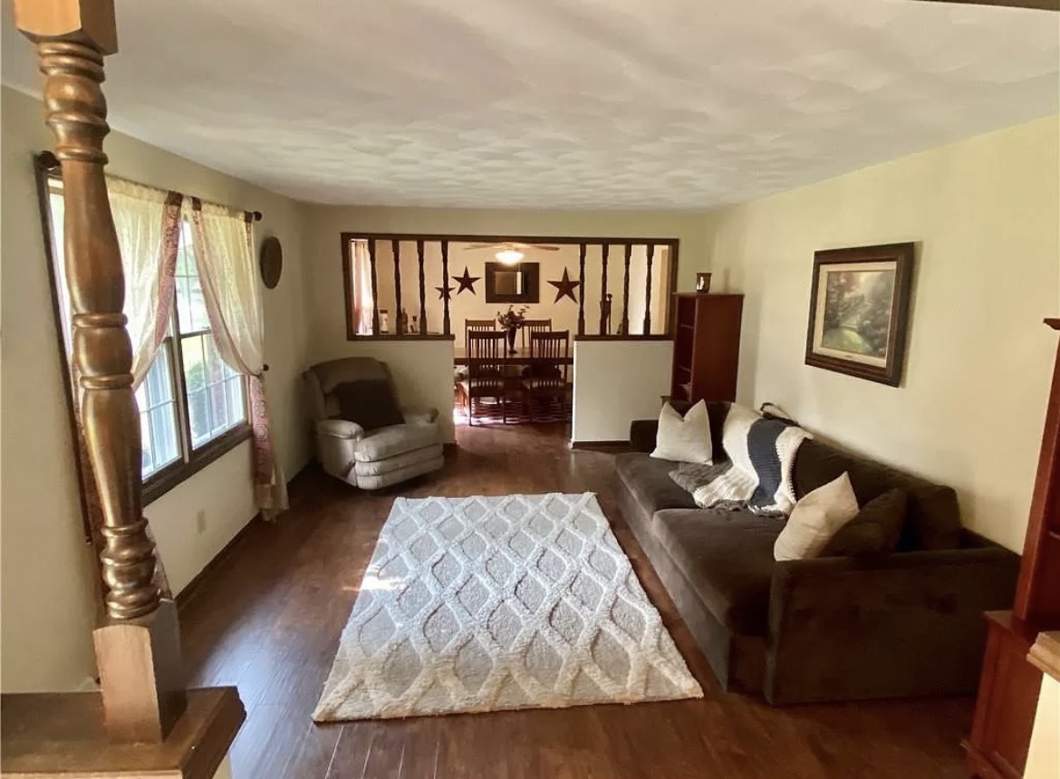 Living room before — dated dark hardwood with heavy trim