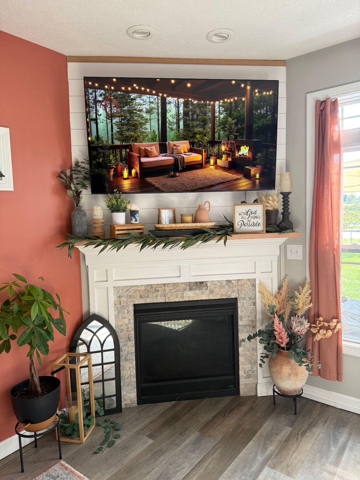 Living room after — warm terracotta accent wall, shiplap surround, mounted TV, and styled mantel