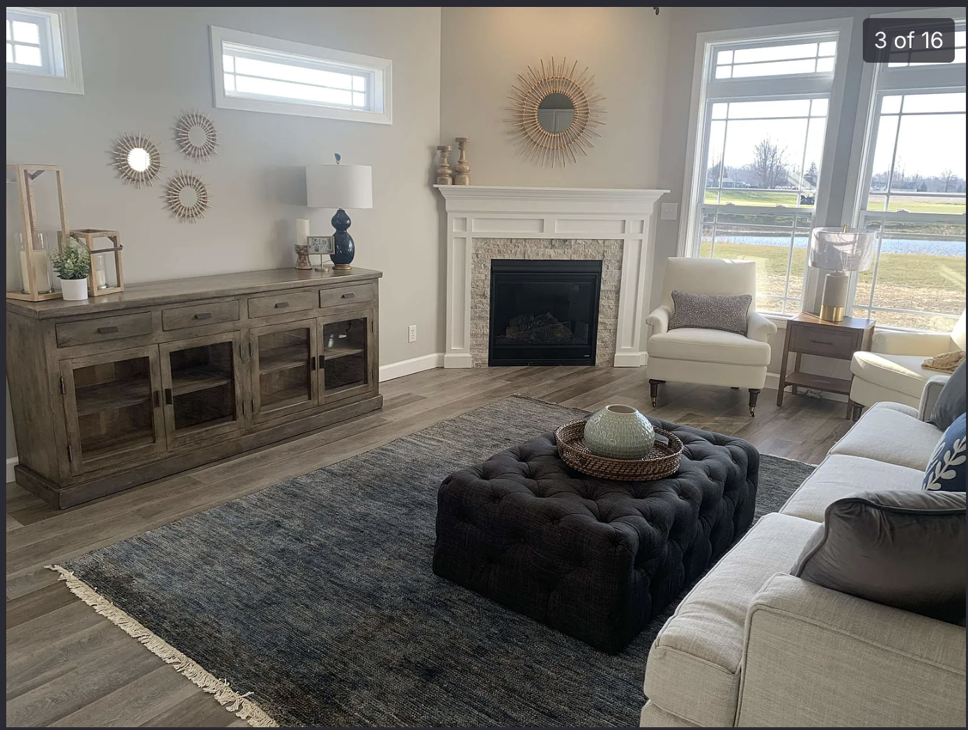 Living room before — neutral gray walls, builder-grade staging around a stone fireplace